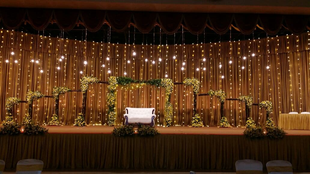 Golden Wedding Stage Golden wedding stage with fairy lights and floral décor by Red Q Events in Kerala